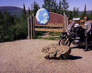 Roy Dyckman poses on his motorcycle in front of a sign along the Dalton Highway in Alaska to the Arctic Circle.