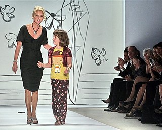 Following the showing of her 2008 spring collection, fashion designer Nanette Lepore reacts to applause as she walks with her daughter Violet Savage on the runway, during Fashion Week in New York, Monday Sept. 10, 2007.