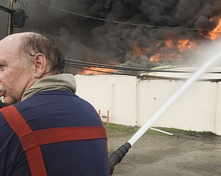 After two hours of battling the fire from the top of a truck, 28-year Youngstown Fire Department Captain Tony Carkido predicted at least another four hours before the area could be deemed safe. Here, Carkido warns other firemen, via radio, that the wall he's hosing may fall any second.