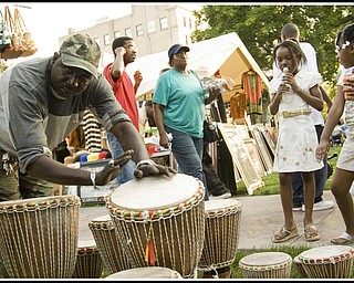 Touba Ndiaye draws a crowd playing the West African Gumbe drums he brought to sell.