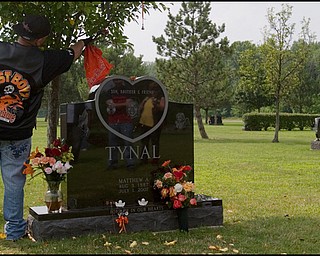 7.6.2008
Dan Sinclair, of Youngstown, hangs an orange bandanna on the tree beside the grave of Matthew Adam Tynal, who died in a motorcycle accident July 1, 2008. "The Lost Boyz" Motorcycle Club was created in honor of Tynal, choosing the colors of his motorcycle, orange, black and white as their own.