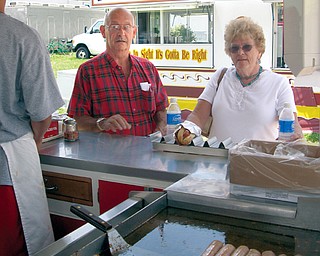 CAN'T WAIT: Ed and Jane Meloni, of Johnston, stand in line for an Italian sausage sandwich at DiRusso's at the Trumbull County Fair. Dominic Fisher, 13, of Canton, served the sausages - made from a family recipe - on the fairgrounds Friday afternoon. Vendors have a variety of foods available for fairgoers to munch on.