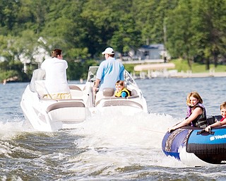 [7.5.2008] Caylah Mccammon (left), age 8, and John Mccamon (right), age 10, both of Canfield ride in an intertube across Lake Milton July 5, 2008. "I've noticed more wave runners on the lake," says John Antonucci who mans the wheel of the boat and enjoys being able to take the kids out but admits, "whipping kids around sure eats up gas."