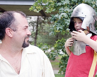 [7.12.2008] Jon Weaver, of Greenville, smiles as Zachary Easton, age 7 of Canfield, tries on a midieval style helmet at a tent belonging to The Society for Creative Anachronism during the ?FESTIVAL OF THE ARTS? along Wick Ave. Saturday afternoon. The group of medieval enthusiasts recreate the tournament style fighting, craft making, drama, music, camping, and cooking of the era citing the importance of learning history beyond simply reading about it and by experiencing it as well. More information can be found at the local chapter's website www.rivenvale.org/ or the national website www.sca.org.
