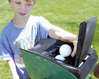 Game on gadget... Andy Garr, 8, of Canfield uses a ball washer while playing in Golf Camp at Mill Creek Park.