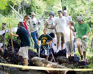 LOTS OF HELP: Members of Scout Troop 40 of Girard, including Jordan Vigorito, third from right, woork on Vigorito's Eagle Scout project at the Lily Pond in Mill Creek Park. They are fixing exposed drainage pipes on the trail surface.
