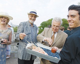 [7.25.2008] Barbara Brothers, Larry Haims, both of Youngstown, and Rolf Nissen, of Warren, enjoy hors d'oeuvres served by Mike Lynch, of Boardman, during a garden party at Fellows Riverside Garden Friday evening.
