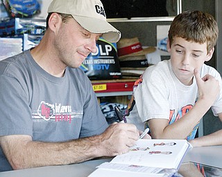 Dave Blaney signs an autograph as his son Ryan, 14, looks on at Sharon Speedway