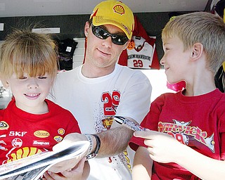 NASCAR driver Kevin Harvick signs autographs for Brooke Cascio, 4, left, and her brother Hunter, 8, at Sharon Speedway Tuesday. They were attending the event with their grandmother Nadine Atkinson of Greenville, Pa.