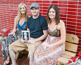 FAMILY AFFAIR: From left, Siblings megan Lewis, 27; Brian Charles, 23; and Molly Charles, 26, site outside the Girard Fire Department where their Father, John Charles, wass a firefighter for more than 20 years. He died from lung cancer last year. The memorial bench has his name engraved on it.