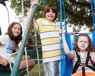 BEING NEIGHBORLY: Twins Kara and Alex Thompson, 11, from left, conducted a fundraiser last month for their neighbor, Sarah Williams, 12, who sits in a special swing in her Poland backyard that her parents bought with donations raised from the benefit.
