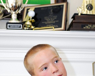 Brian Terlesky, 8, of Boardman stands in front of some of his trophies in his home. Brian dreams of playing in a PGA tournament one day.