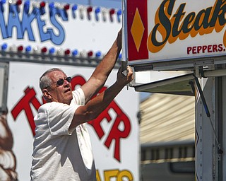 HANGIN IN THERE: Bob Taylor of Cortland hangs his signs on his booth at the Canfield Fair.