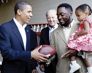 Democratic presidential candidate, Sen. Barack Obama, D-Ill., and his vice presidential running mate Sen. Joe Biden, D-Del., center, gets a football autographed by Pittsburgh Steelers coach Mike Tomlin as he holds his daughter, Harlynn Quinn Tomlin, 2, in Pittsburgh, Pa., Friday, Aug. 29, 2008.