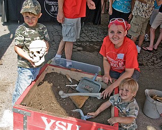 Edwina Baier, a senior Youngstown State University anthropology major, helps Joe Winters, 4, and Jack Winters, 2, both of Knox, Pa., dig for artifacts and one real skull hidden in the box until unearthed by brooms and trowels.