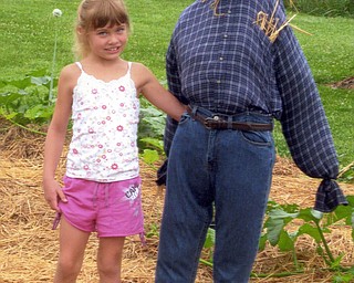 Natashia Salmen, 7, of Leetonia is rightfully proud of her scarecrow and her vegetables, which she enters in the Canfield Fair. Her grandmother, Nora Salmen of Columbiana, points out that these veggies are all Natashia's because she planted, tended and harvested everything.