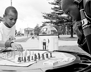 A MEETING OF THE MINDS: Ce'Andre Backus, 10, of Youngstown, left, plays chess with Kyron Lee, 12, of Youngstown as Star Wars' R2D2 tech-celebrity observes at the Stop The Violence block party in Youngstown's Wick Park.