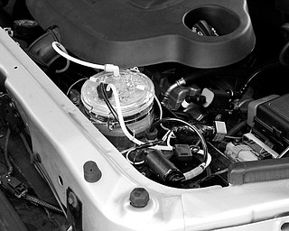 POWER BOOSTER: Some local inventors have come up with a hydrogen generator they say boosts fuel efficiency by 50 percent. The device, about the size of a candle jar and with a clear lid, is shown in the center of this photo, installed in an engine compartment owned by Ohio’s Hydrogen Innovation Organization, the company founded by the inventors.