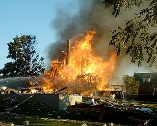 A neighboring residence caught fire after a house on the corner of Townsend and Washington Streets in Girard exploded Thursday, July 18, 2008. Photo by James Hughes.  