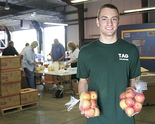 Cory Kranek (age 15) of Boardman is holding bagged apples at Second Harvest Food Bank on Saturday where he volunteered and packed food bags.