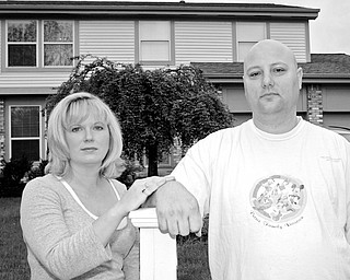 MOVING OUT: Jamie and John Petree stand in front of their home in Gahanna, Ohio, as they move out. The Petrees say that previous owner Andrew Zukowski, who had lost the house in a bank foreclosure, has tried to scare them away for eight years.