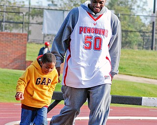 BIG AND SMALL STEPS: Aidan Slocum, 6, of Boardman walks with YSU basketball player Jack Liles of Maryland in the inaugural Coaches vs. Cancer 3-mile walk at Youngstown State University's outdoor track. Aidan is the grandson of head coach Jerry Slocum of Boardman.
