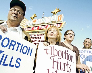 TAKING A STAND: (Left to right) Pastor Nick Furrie, of Shiloh Gospel Church in Girard, Carolyn Furrie, Savanna Frantz, 12, of Girard, up anti-abortion signs on Elm Road Northeast in Warren during an anti-abortion demonstration Sunday.