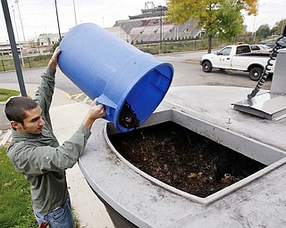 Dan Kuzma, YSU recycling manager dumps bark mulch into a food waste composting device outside Christman Dining Hall on the YSU campus Monday. Mulch is mixed with food waste and turned into compost to be used on campus.