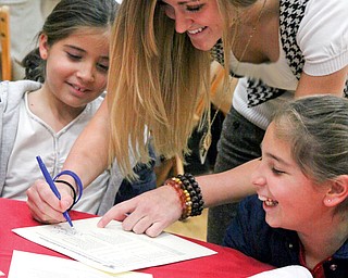 Kelsey Gurganus, middle, of YSU's womens basketball team gives her autograph to Marissa, left and Gianna Lellio of Lowellville, right.