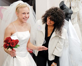 BEAUTIFUL AND FREE: Judy Gibbons of Macedonia tries on a wedding dress at Evaline’s Bridal store in Warren. Beside her, shop owner Lori Dubasik assists Gibbons with her dress during an event giving military brides free and deeply discounted dresses.