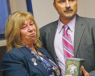 Tom Siesto and his wife, Liz Raab with a tin containing Nitro’s ashes. The Rottweiler weighed 50 pounds when cremated; he weighed 105 pounds when taken to High Caliber K-9 in late June for obedience training. His owners said they paid more than $2,000 up front for the training and dropped him off with more than three months’ food and vitamins.