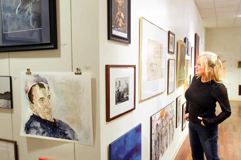 Judy Kay, a volunteer at the Art Outreach center in the Eastwood Mall looks over art on display there. 