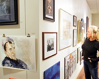 Judy Kay, a volunteer at the Art Outreach center in the Eastwood Mall looks over art on display there.