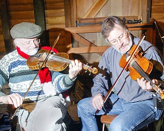 Fiddlers Dennis Kempthorne, left, of Homeworth and Frank Krygowski of Poland were among the traditional entertainers at the Christmas at the Old Mill in Mill Creek Park Sunday. They were playing traditional Irish and American folk songs.