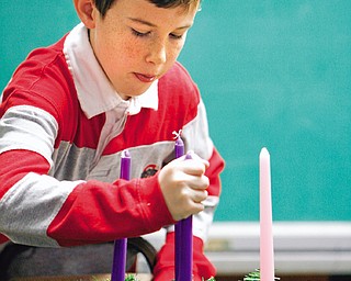 Mathew Weingart puts in the advent candles into his wreath as he puts the finishing touches on his advent wreath at St Paul Church in Salem