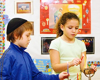 Dylan King and Abigail Sharf third graders at Akiva Academy light the Menora - Each night during Chanukah Jews light candles in a special candelabra called a Menorah (Hebrew: Hanukiyah). The center candle, called the Shamash, is always the first candle placed in the Menorah and the first candle to be lit each night. The remaining candles are placed and lit in a specific order depending on the night of the celebration.