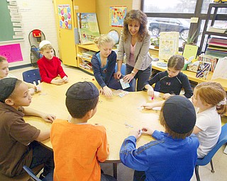 Tirtra Kohan, third grade teacher at Akiva Academy in Liberty, watches as her student play the dreidel - it is one of the best known symbols of Chanukah. A four-sided top with a Hebrew letter on each side, the dreidel is used to play a fun Chanukah game of chance.