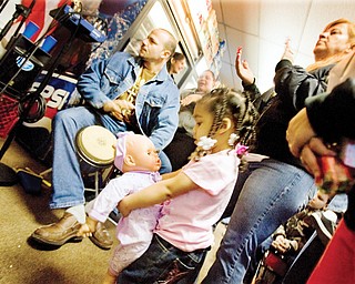 Neymari González, age 2 of Youngstown, dances with a baby doll while Maria Torres claps her hands and Jose Gonzalez plays the drums at Saborico Corner Market in Youngstown. Music followed an appearance by the three kings (played by local high school students) who visited the store and distributed toys to local youngsters.