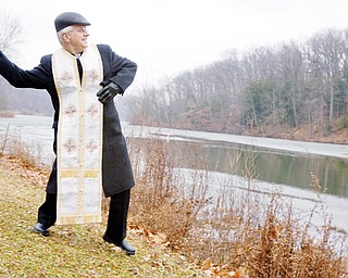 Father Daniel Rohan, of St. Marks Orthodox Church in Liberty, throws a wooden cross into Lake Glacier at Mill Creek Metro Park during The Great Blessing of Water ceremony held Tuesday afternoon.