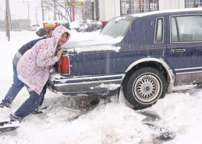 Sean Runkle and his son Isaiah of Youngstown push their Lincoln Towncar after getting stuck in the McDonald's parking lot on Mahoning Ave, Saturday January 10, 2009