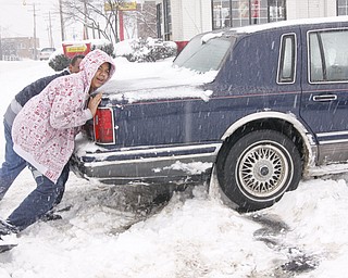 Sean Runkle and his son Isaiah of Youngstown push their Lincoln Towncar after getting stuck in the McDonald's parking lot on Mahoning Ave, Saturday January 10, 2009