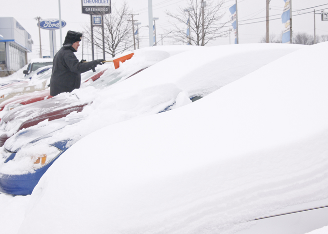 Sales and Leasing Professional Dennis Sima scrapes snow off of a Red Chevy Cobalt at Greenwood Chevrolet, Saturday January 10, 2009