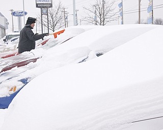 Sales and Leasing Professional Dennis Sima scrapes snow off of a Red Chevy Cobalt at Greenwood Chevrolet, Saturday January 10, 2009