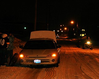 An ATV pulls a sled down Lowellville Road as others change a tire.