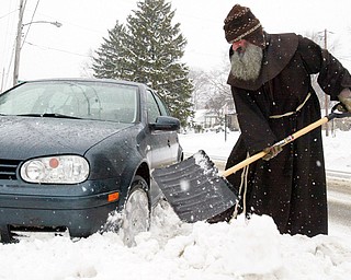 Rev. Vit Fiala, a priest at Shrine of Our Lady, Comforter of the Afflicted, 517 S. Belle Vista Ave in Youngstown, digs his car out after sliding into a snowbank in front of the shrine Tuesday. With the help of a few passing motorists and a Vindicator photographer he was on his way.