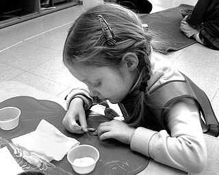 PRESENTABLE PENNIES: Lilly Weiss of Canfield, a 4-year-old pupil at Montessori School of the Mahoning Valley, cleans a stack of pennies using salt, vinegar, water and a cotton swab as part of the school's Pennies for Peace contribution. The cleaning process builds patience and fine motor control.
