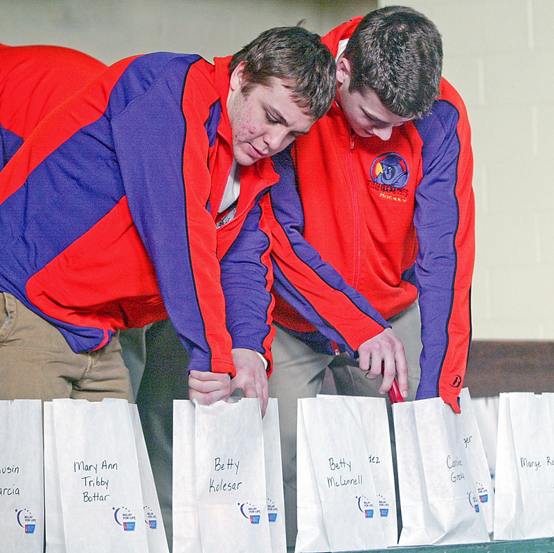 Youngstown Phantoms players Johnny Meo, left, and Doug Clifford light luminaries during a Relay for Life event at St Patrick School in Hubbard Monday.