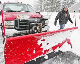 Snowplow driver Carl Dohar of Arrow Asphalt checks his plow while working in Liberty.