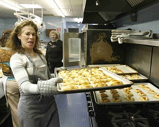 Rachelle Miller pulls hot cookies out of the oven as the church makes Hamentaschen cookies for Purim- robertkyosay