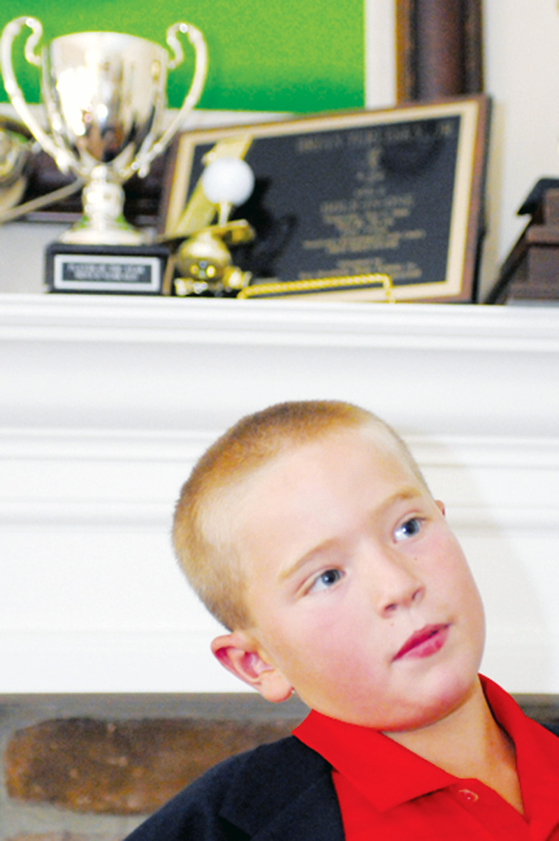 Brian Terlesky, 8, of Boardman stands in front of some of his trophies in his home. Brian dreams of playing in a PGA tournament one day. 